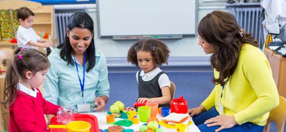 two adults sat with EYFS children 